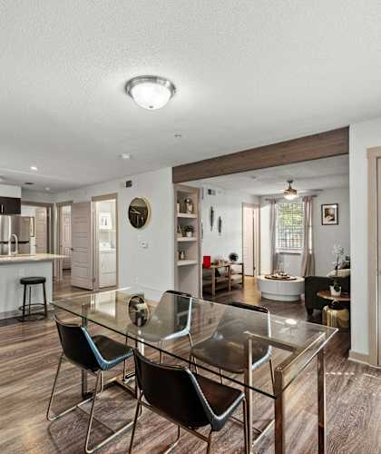 A modern kitchen with a glass table and bar stools.