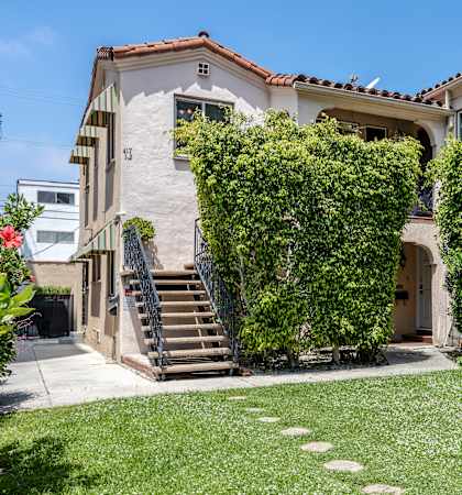 a house with a staircase and hedges in front of it