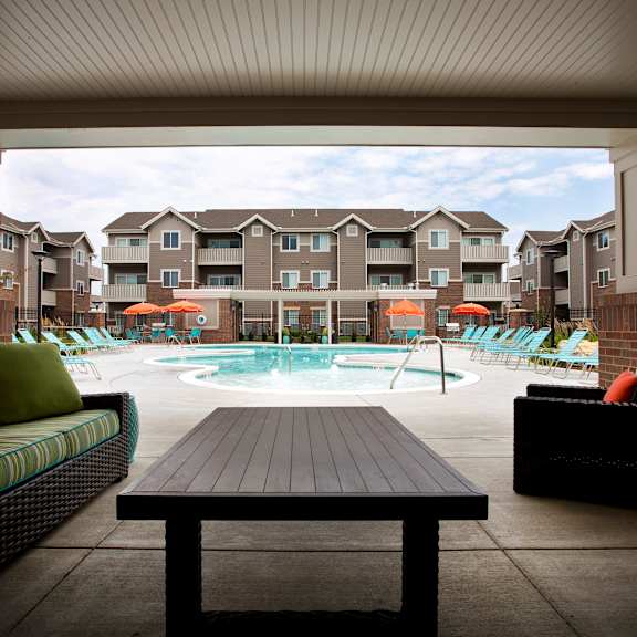 A patio with a table and chairs overlooking a pool.