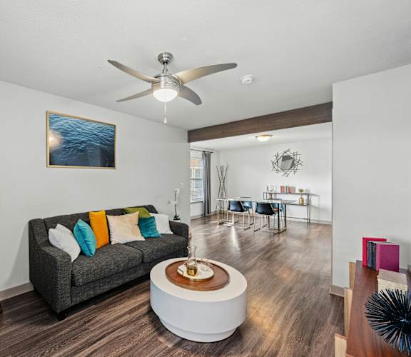 A living room with a grey couch and a wooden floor.