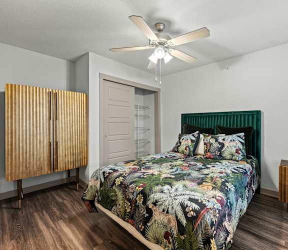 A bedroom with a bed, a wooden cabinet, and a ceiling fan.