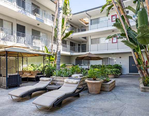 a courtyard with lounge chairs and umbrellas