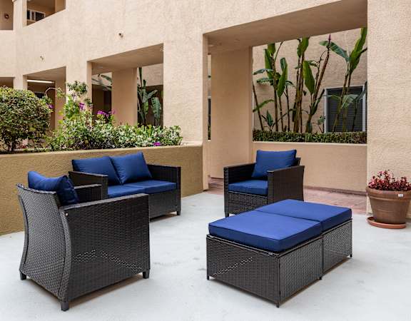 a seating area with two chairs and a coffee table on a concrete patio in front of a