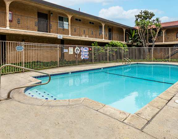 a swimming pool with a fence around it and a building in the background