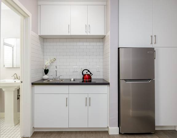 a small kitchen with white cabinets and a stainless steel refrigerator