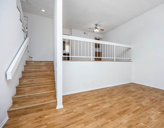 a bedroom with hardwood floors and a staircase