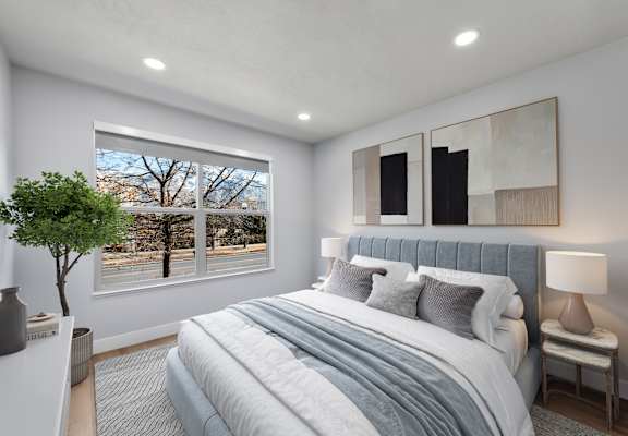 A bedroom with a large bed and a window overlooking a tree-lined street.