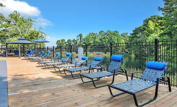 an outdoor deck with chaise lounge chairs and a black fence