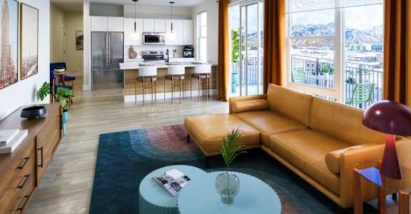 A living room with a tan couch and a glass table with a plant on it.