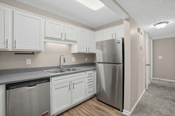 A kitchen with a stainless steel refrigerator and white cabinets.