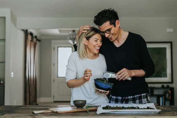 A man and woman are preparing food together in a kitchen.