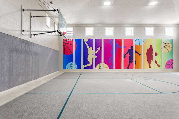 A basketball court with a wooden floor and a basketball hoop.