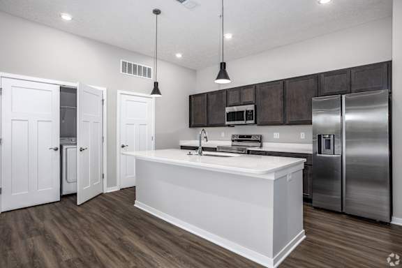 A modern kitchen with white countertops and stainless steel appliances.