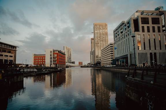 A cityscape with buildings reflected in the water.