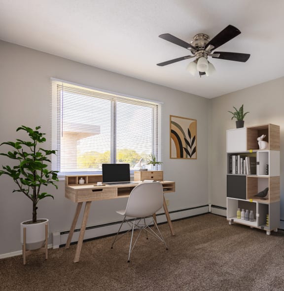 an office with a ceiling fan and a desk with a laptop