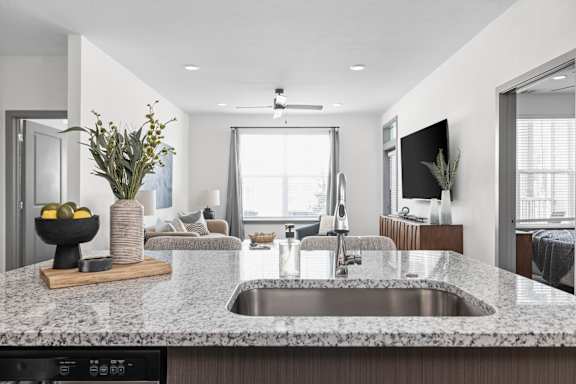 A modern kitchen with a granite countertop and a stainless steel sink.