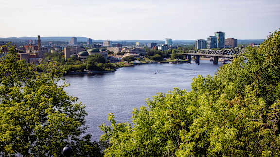 A cityscape with a river and a bridge in the background.