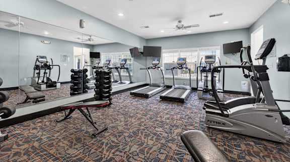 A gym with a variety of equipment including treadmills, weights, and exercise machines.