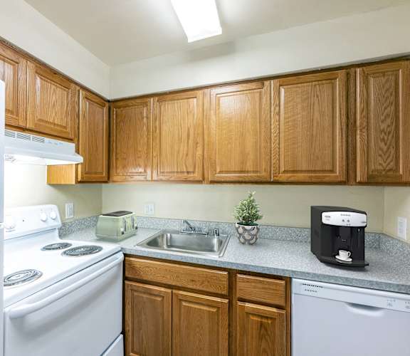 an empty kitchen with white appliances and wooden cabinets