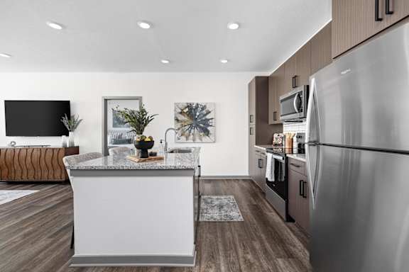 A modern kitchen with a white island and stainless steel appliances. Standard441 Luxury Apartment Homes, Lady Lake, FL, 32159