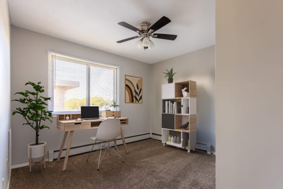 an office with a ceiling fan and a desk with a laptop