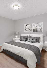 A bedroom with a bed, nightstand, and chair.