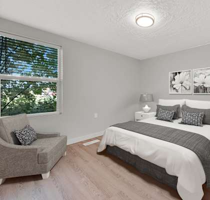 A bedroom with a bed, nightstand, and chair.