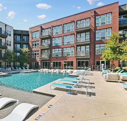 a swimming pool with lounge chairs in front of an apartment building