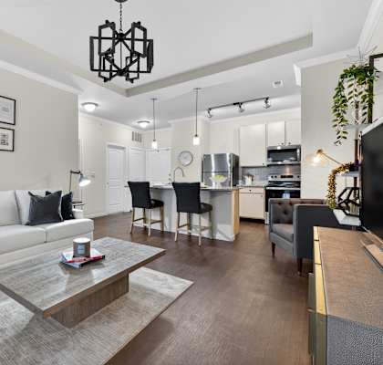 A modern living room with a white sofa, a coffee table, and a dining area in the background.