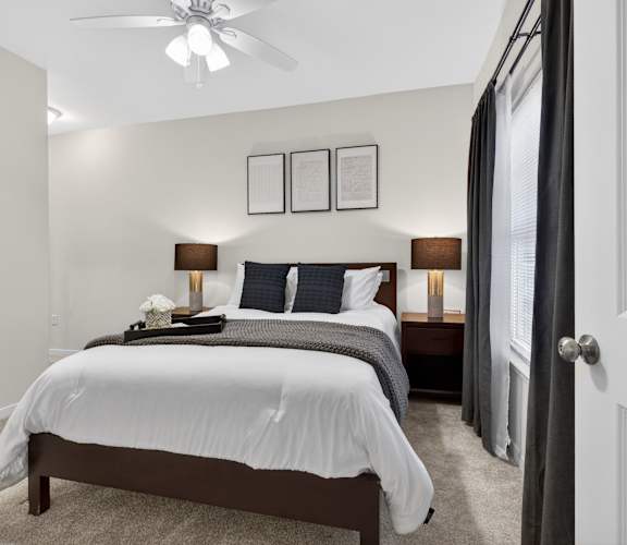 A bedroom with a bed, nightstand, and a ceiling fan.