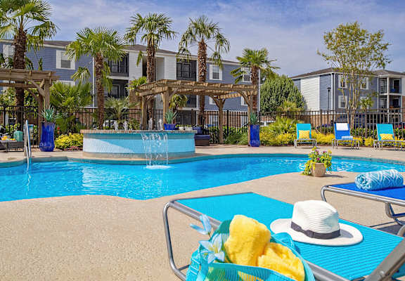 A poolside scene with a hat, sunglasses, and pineapple chunks.