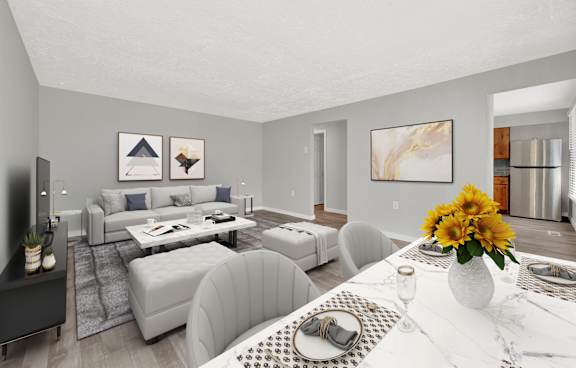 A modern living room with a grey sofa set and a white dining table set with a vase of sunflowers.