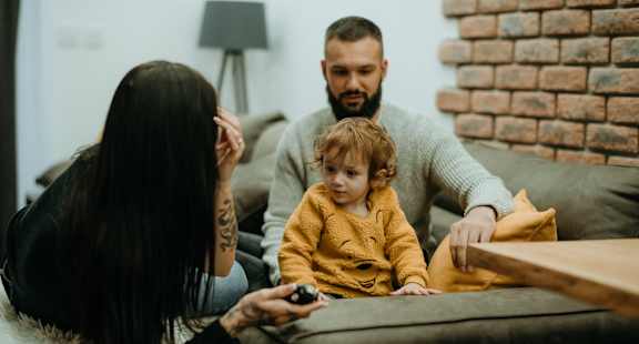 a young child sitting on a couch with a family