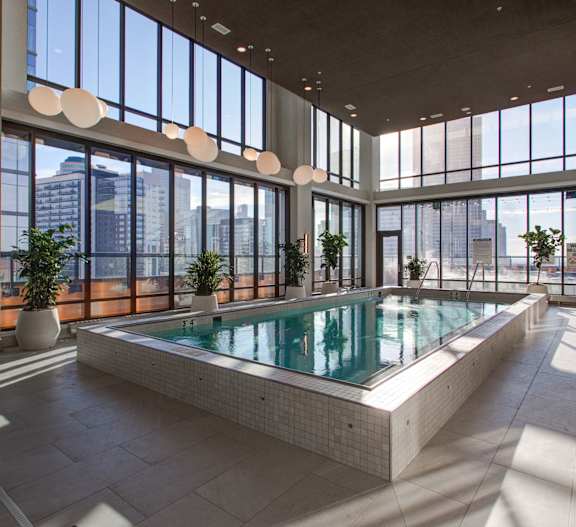 A large indoor swimming pool with a view of the city outside the windows.