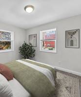 A bedroom with a bed, pillows, and pictures on the wall.