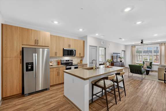 A modern kitchen with wooden cabinets and a stainless steel refrigerator.