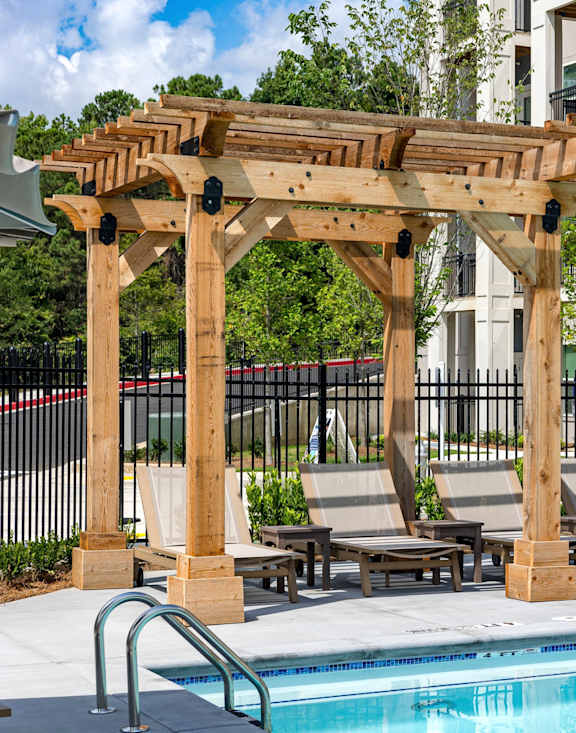 A wooden pergola over a pool with lounge chairs underneath at The Collective Upper Westside Apartments, Atlanta, GA, 30318