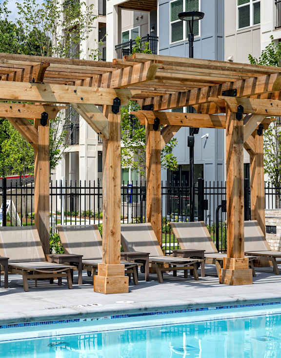 A wooden pergola over a pool with lounge chairs underneath at The Collective Upper Westside Apartments, Atlanta, GA, 30318