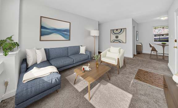 A living room with a blue couch, a white chair, and a painting on the wall.