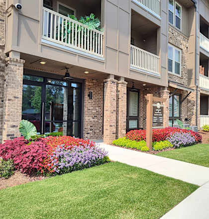 an exterior view of an apartment building with a sidewalk and landscaping
