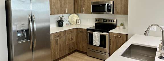 A kitchen with a stainless steel refrigerator, microwave, oven, and sink at The Collective Upper Westside Apartments, Atlanta, GA, 30318