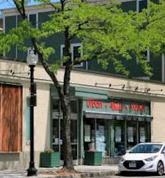 A white car is parked in front of a building with a sign that says "Findlay's Market".