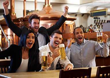 Four people are celebrating with beer glasses in a bar. at Residences at Addison Clark, Chicago, 60613