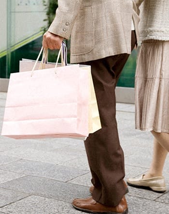two people walking down the street holding shopping bags