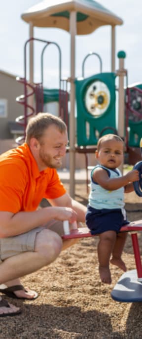 a man playing with a child on a playground toy