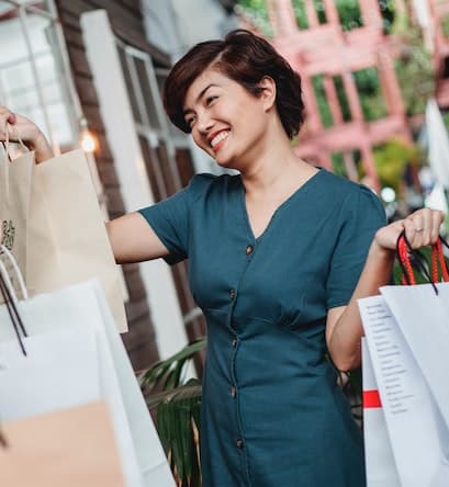 a smiling woman carrying shopping bags outside