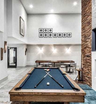 A pool table is in the middle of a room with a brick wall.