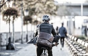 a person riding a bike with a leather bag on the back