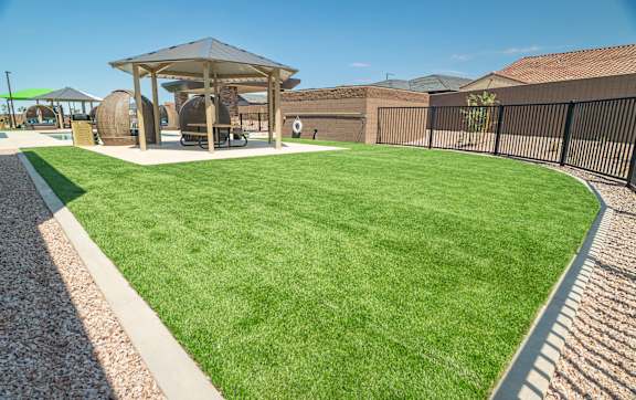 A well-maintained lawn with a gazebo and a playground in the background.
