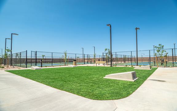 A park with a fence, bench, and tennis court.